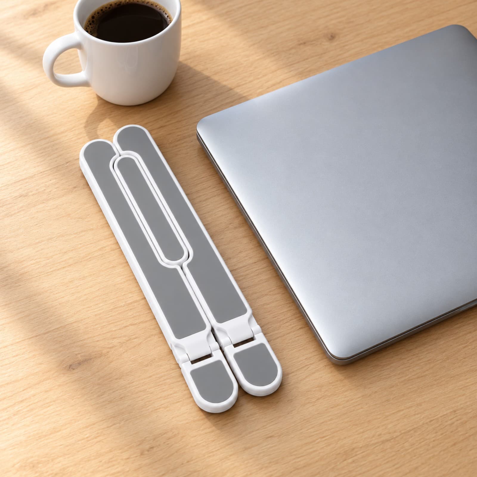 Soporte plegable para notebook P1 blanco plegado, apoyado sobre un escritorio junto a una notebook cerrada y una taza: ocupa poco lugar; la notebook no está incluida (imagen ilustrativa), SOPNOTMETGR — miniatura 6