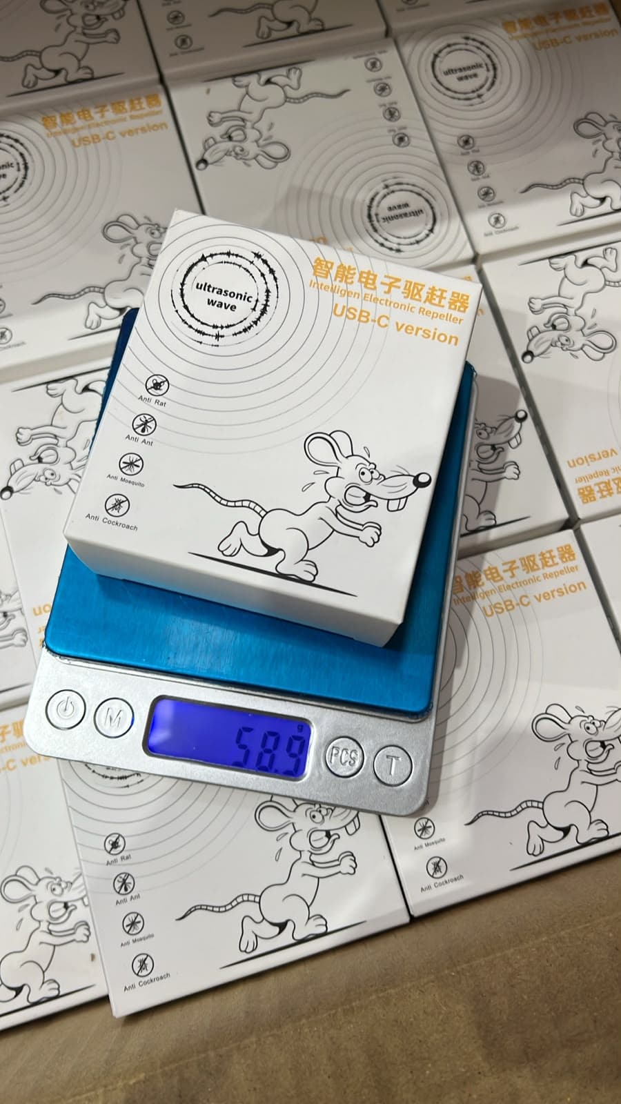 Foto real de la caja del repelente W27 USB-C sobre una balanza que marca 58,9 g, REPPLAGAB — miniatura 8